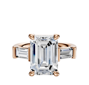 The 18K Rose Gold 3-Stone Baguette East/West Side Stones 0.25TCW Engagement Ring features a large emerald-cut center stone with two smaller baguette side stones in a prong setting, shown against a white background.