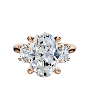 The 14K Rose Gold 3-Stone Oval Side Stones 0.25TCW Engagement Ring features an oval center diamond with two smaller oval side stones in prong settings.
