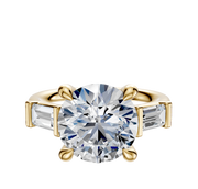 The 14K Yellow Gold 3-Stone Baguette East/West Side Stones 0.25TCW Engagement Ring features a central round diamond with two baguette side stones, all set on a plain band and photographed against a white background.