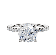The 14K White Gold 4 Prong Basket Classic Dome 1-Row-Pave 2.5mm Engagement Ring features a round center stone held by four prongs and a band adorned with a row of sparkling pave-set diamonds.