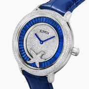 The 38MM Swiss Made Stainless Steel Spinning Starfish Watch features diamonds, blue topaz, a blue leather strap, silver face with blue accents, silver hands, the EARY logo on the dial, and a jeweled starfish motif near the bottom.