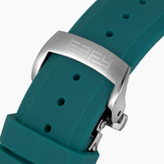 The 42MM Swiss Made Stainless Steel Automatic Skeleton Watch with Diamonds features a teal rubber strap, silver case, partially transparent dial with visible gears, teal bezel and markings, and EBFY branding at the top.