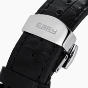 The 36MM Black Dial Swiss Made Titanium Watch with Diamonds features a faceted silver titanium case, black dial adorned with diamond hour markers, and a black leather strap, showcased against a plain white background.