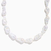 A close-up of the 14K Yellow Gold Freshwater Baroque Pearl Necklace featuring irregularly shaped white pearls and a 14K yellow gold clasp, set against a white background.