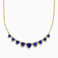 The Nahla 14K Yellow Gold Trillion Tanzanite and Diamond Necklace showcases seven deep blue trillion tanzanites, each framed by diamonds and evenly spaced along the chain.