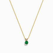 The 14K Yellow Gold Solitaire Round Emerald Pendant (0.48 TCW) features a delicate gold chain and a small round emerald, showcased against a white background.