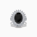 The 14K White Gold Onyx and Diamond Double Halo Ring features a large oval onyx surrounded by two rows of sparkling white diamonds, set on a white gold band and displayed against a white background.