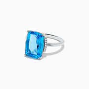 The Ocean Bleu 14K White Gold Blue Topaz and Diamond Ring showcases a large rectangular Blue Topaz gemstone, accented by sparkling diamonds on either side of the band.