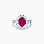 The 18K White Gold Ruby and Diamond Halo Ring features an oval red ruby at the center, encircled by a diamond halo, beautifully presented on a plain white background.