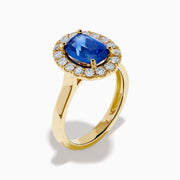 The Royale Bleu 18K Yellow Gold Blue Sapphire and Diamond Halo Ring showcases a striking oval blue sapphire centerpiece surrounded by a sparkling diamond halo.