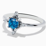 The 14K White Gold Blue and White Diamond Ring features a round blue diamond center with small white stones in a compass pattern, displayed on a white background.