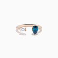The 14K Rose Gold Blue and White Diamond Toi Et Moi Ring features an open design with a clear rectangular diamond and a blue teardrop diamond, elegantly displayed on a white background.