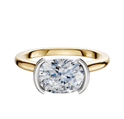 An 18K two-tone bezel half bezel East/West cathedral dome engagement ring (2.0mm) with a large cushion-cut diamond, set in a modern setting with white metal prongs, displayed on a plain white background.