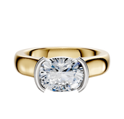 The 18K Two Tone Bezel Half Bezel East/West Cathedral Dome 4.0mm Engagement Ring features a broad band and a large diamond in a modern half bezel east/west setting with white metal prongs on each side.