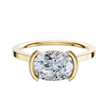 An 18K Yellow Gold Bezel Half Bezel East/West Cathedral Flat 1.5mm Engagement Ring is displayed with a large cushion-cut diamond in a modern bezel-style setting against a plain white background.