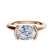 The 18K Rose Gold Bezel Half Bezel East/West Cathedral Knife Edge 2.0mm Engagement Ring features a large, round-cut diamond in a modern four-prong bezel setting, displayed on a white background.