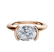 An 18K rose gold half bezel east/west classic knife edge 2.0mm engagement ring is shown with a large, round brilliant-cut diamond in a modern minimalist setting against a plain white background.