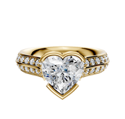 An 18K yellow gold engagement ring with a knife edge and half bezel east/west cathedral setting, featuring a central diamond and a single row of pave-set diamonds along the 2.5mm band.