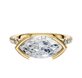 The 18K Yellow Gold Bezel Half Bezel East/West Cathedral Dome Engagement Ring features a large center diamond held in an east-west setting, accented by a row of pave diamonds along the 2.5mm band, shown against a white background.