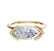 An 18K yellow gold East/West Classic Knife Edge engagement ring featuring a large marquise-cut clear gemstone in a half bezel setting, displayed against a plain white background.