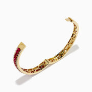 The 18K Yellow Gold Ruby and Diamond Bangle features a honeycomb-patterned interior, with a row of rubies bordered by two rows of sparkling diamonds on the outside.
