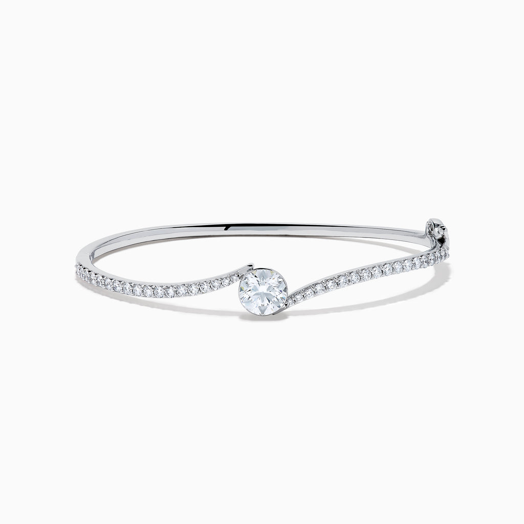The Star Lab Grown Diamond Connect Bangle in 18K White Gold features a central round lab-grown diamond and a band set with small diamonds, all in an elegantly curved design, displayed on a white background.