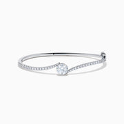 The Star Lab Grown Diamond Connect Bangle in 18K White Gold features a central round lab-grown diamond and a band set with small diamonds, all in an elegantly curved design, displayed on a white background.