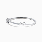 The Star Lab Grown Diamond Connect Bangle in 18K White Gold features a central round lab-grown diamond and a band set with small diamonds, all in an elegantly curved design, displayed on a white background.