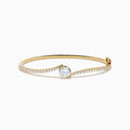 The Star Lab Grown Diamond Connect Bangle in 18K Yellow Gold features a central Star Lab Diamond with a row of smaller diamonds on an angled band, shown against a white background.