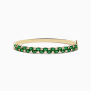 The 14K Yellow Gold Emerald and Diamond Bangle features two rows of round emeralds bordered by smaller diamonds, with a side clasp.