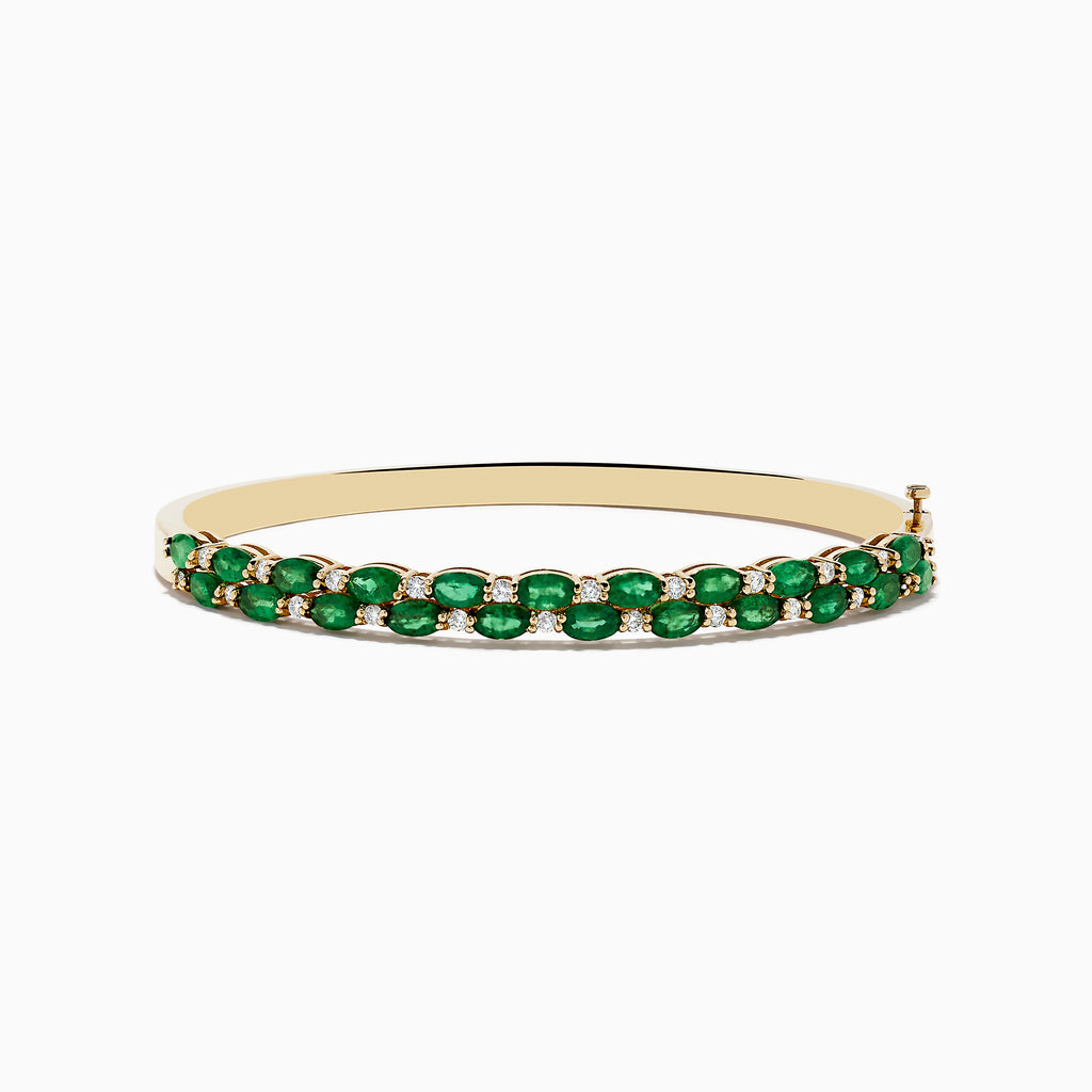 The 14K Yellow Gold Emerald and Diamond Bangle features two rows of round emeralds bordered by smaller diamonds, with a side clasp.