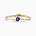 The 14K Yellow Gold Tanzanite and Diamond Chain Link Bracelet features a central triangular tanzanite gem, accented by rows of sparkling diamonds and a polished gold chain link band with a secure clasp.