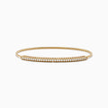 The 14K Yellow Gold Flexible Diamond Bangle features a slender design with sparkling diamonds set along the top half, shown against a white background.