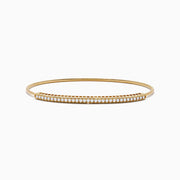 The 14K Yellow Gold Flexible Diamond Bangle features a slender design with sparkling diamonds set along the top half, shown against a white background.