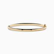 The 14K Yellow Gold Hollow Bangle features a smooth, round design with a small clasp, crafted in polished yellow gold and displayed on a white background.