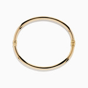 The 14K Yellow Gold Hollow Bangle features a smooth, round design with a small clasp, crafted in polished yellow gold and displayed on a white background.