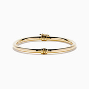 The 14K Yellow Gold Hollow Bangle features a smooth, round design with a small clasp, crafted in polished yellow gold and displayed on a white background.