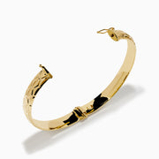 The 14K Yellow Gold Textured Hinge Bracelet features a shiny finish and a geometric diamond-patterned texture around its outer surface, shown on a white background.