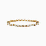 The 14K Yellow Gold Opal and Diamond Tennis Bracelet features a row of round white opals set in gold prongs, accented with diamonds, displayed on a white background.