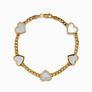 The 14K Yellow Gold Mother of Pearl and Diamond Heart Chain-link Station Bracelet features five white heart-shaped charms bordered with sparkling stones, evenly spaced along a gold chain.