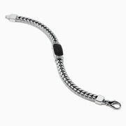 The Mens Sterling Silver Black Spinel Bracelet features a woven chain, a rectangular textured black spinel centerpiece, and a secure clasp closure, shown on a white background.