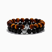 The Tiger's Eye and Onyx Beaded 2-Piece Bracelet Set with Sterling Silver features brown and black beads, each bracelet accented by a single sterling silver bead with a textured, woven pattern for an elegant stacked look.