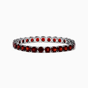 The 925 Sterling Silver Garnet Bracelet features round, deep red garnets set in individual prongs along a sleek tennis chain, beautifully arranged in a circular shape on a white background.