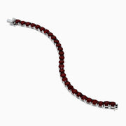 The 925 Sterling Silver Garnet Bracelet features round, deep red garnets set in individual prongs along a sleek tennis chain, beautifully arranged in a circular shape on a white background.