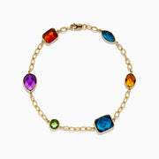 The Mosaic 14K Yellow Gold Multi Gemstone Station Bracelet features five colorful gemstones—blue, green, orange, red, and purple—in various shapes along a gold chain. Shown on a white background, it’s a vibrant accessory for any occasion.