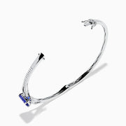 The 14K White Gold Tanzanite and Diamond Bangle showcases a striking round tanzanite centerpiece, accented by rows of sparkling diamonds along the band.