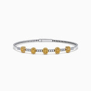 The Canare Platinum and 18K Yellow Gold Yellow and White Diamond Bangle features five oval yellow gold accents, each set with yellow diamonds, spaced along clear square-cut white diamonds for a sleek, elegant look.