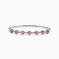 The 14K White and Rose Gold Light Pink and White Diamond Bangle features a sleek silver band with seven clusters of light pink diamonds, each separated by a small white gemstone.