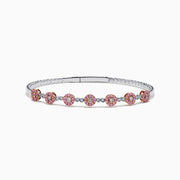 The 14K White and Rose Gold Light Pink and White Diamond Bangle features a sleek silver band with seven clusters of light pink diamonds, each separated by a small white gemstone.