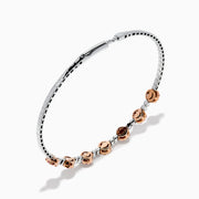 The 14K White and Rose Gold Light Pink and White Diamond Bangle features a sleek silver band with seven clusters of light pink diamonds, each separated by a small white gemstone.